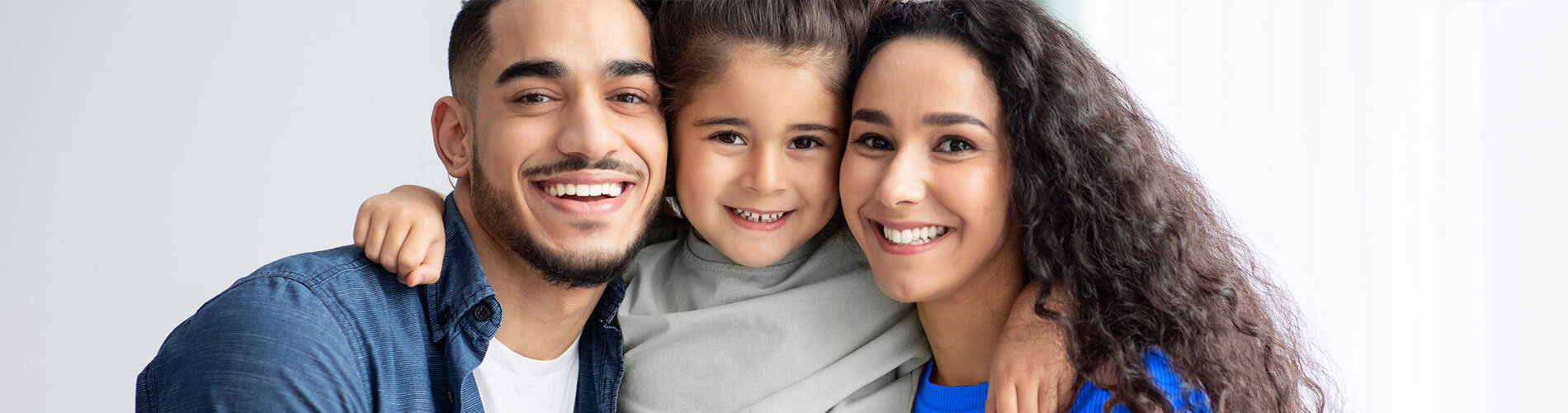 Mother, father and their young child and faced forward and smiling